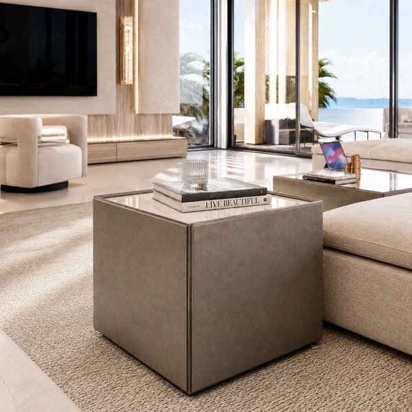 Square end table beside pale upholstered seating in a bright living room.