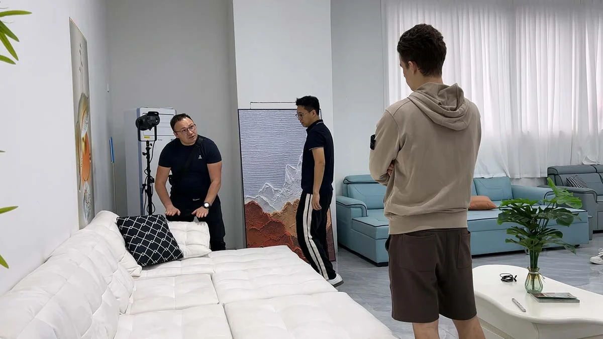 Several people examining a white upholstered sofa in an interior workspace