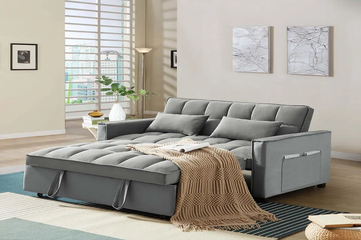 Grey sleeper sofa opened into a broad upholstered sleeping surface with the back and arms still visible