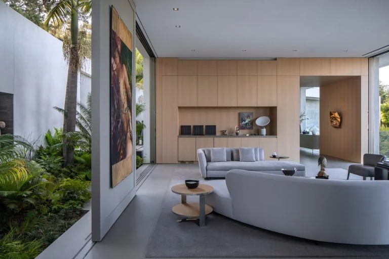 Curved gray sofa and small tables in a living area open to a garden
