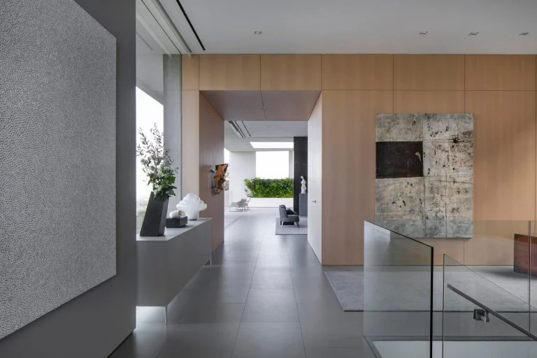Long interior passage with wood wall panels, console surfaces and artwork