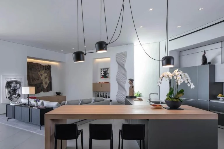 Long wood dining table with dark chairs and pendant lights in an open room
