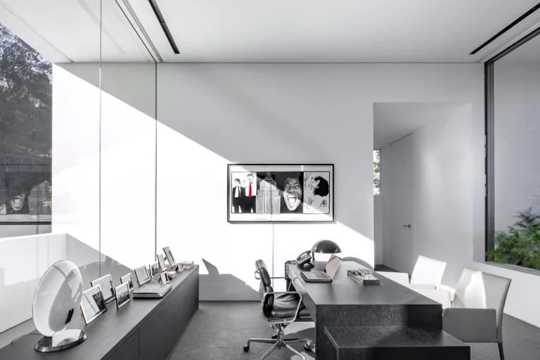 Bright home office with a long desk, several chairs and a wall screen